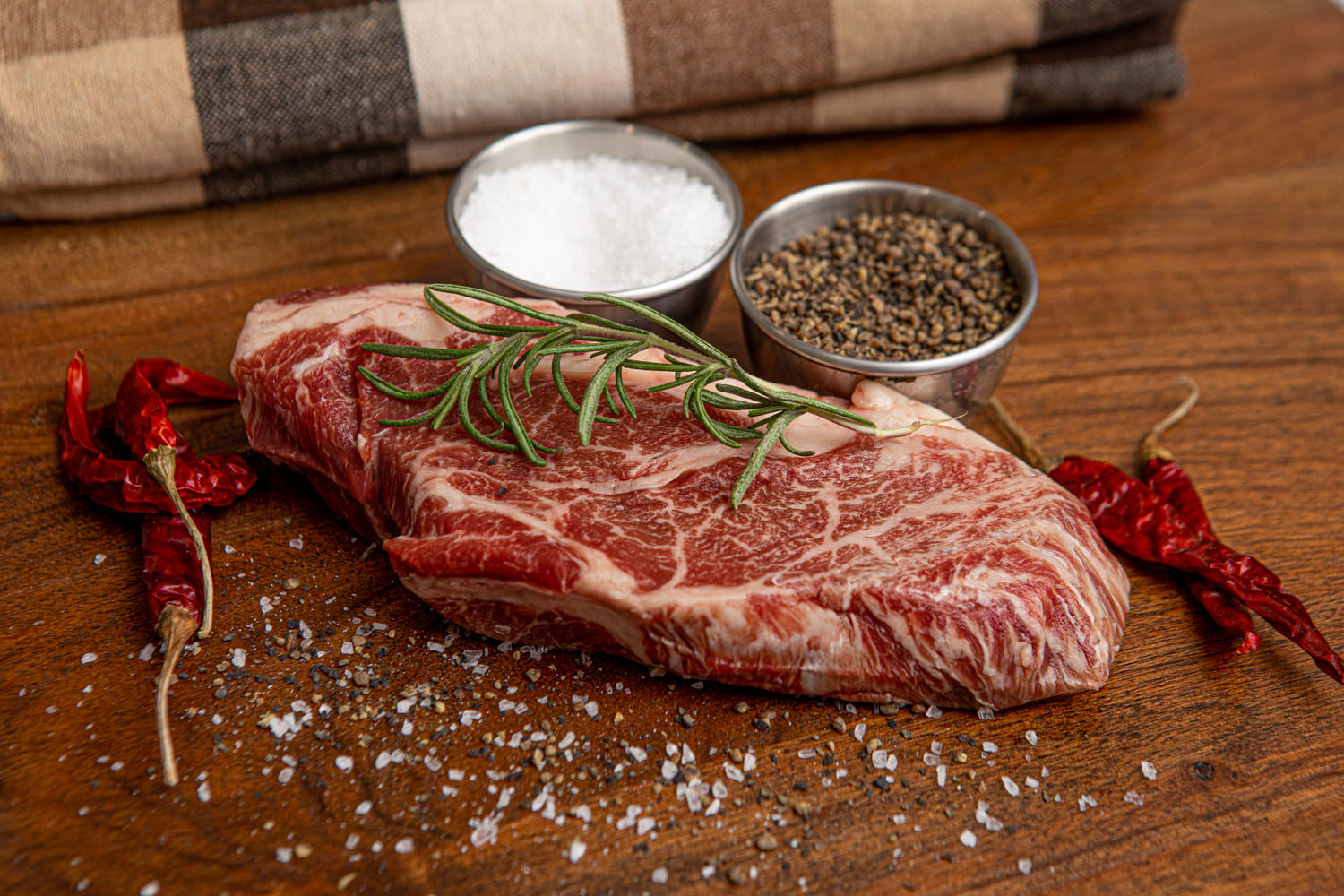 Kosher Wagyu Chuck Steak with seasonings on Wooden table available at Chu's Meat Market