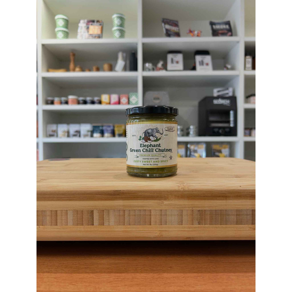 Jar of Elephant Green Chili Chutney on a wooden surface with shelves in the background