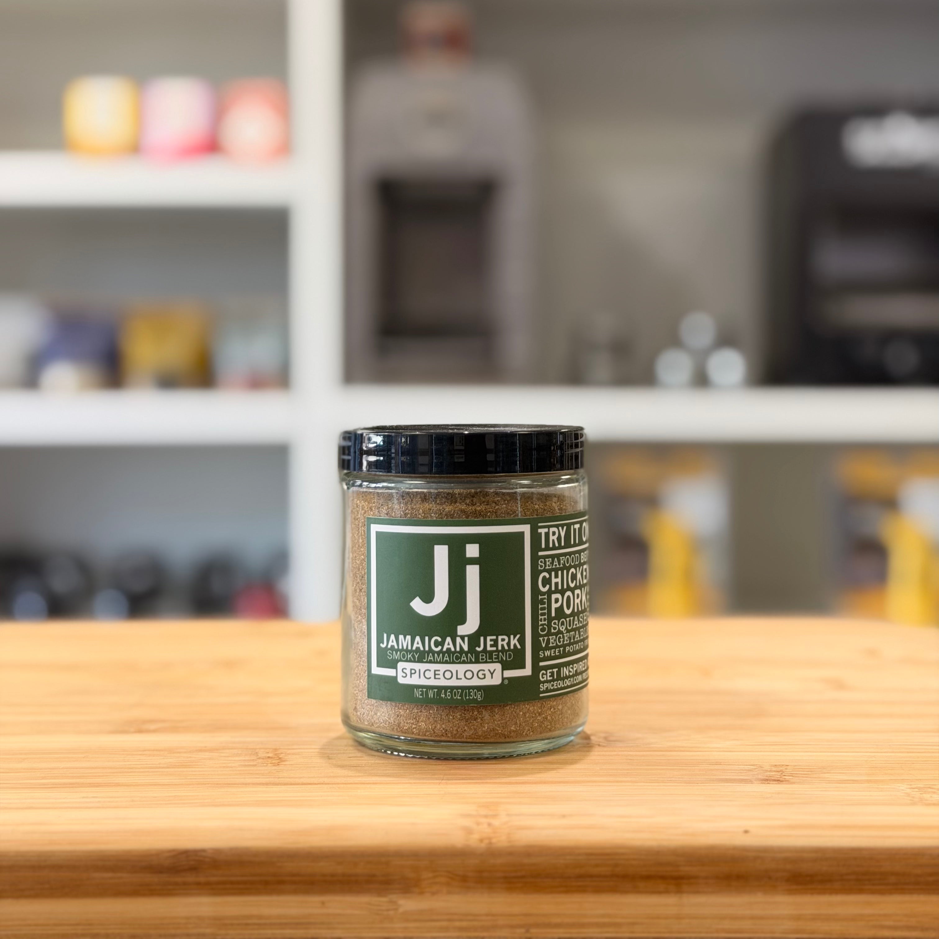 Jamaican jerk spice jar on a wooden surface with a blurred kitchen background