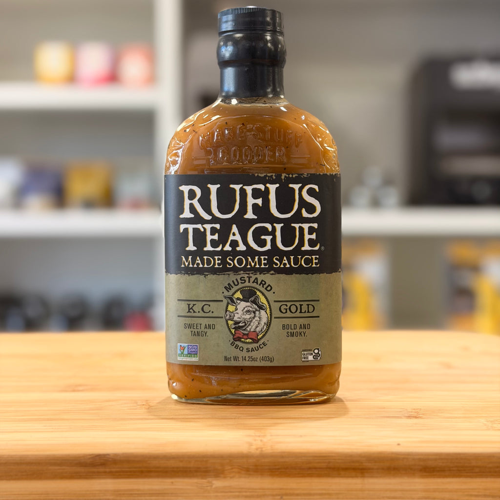 Bottle of Rufus Teague mustard on a wooden surface with a blurred kitchen background