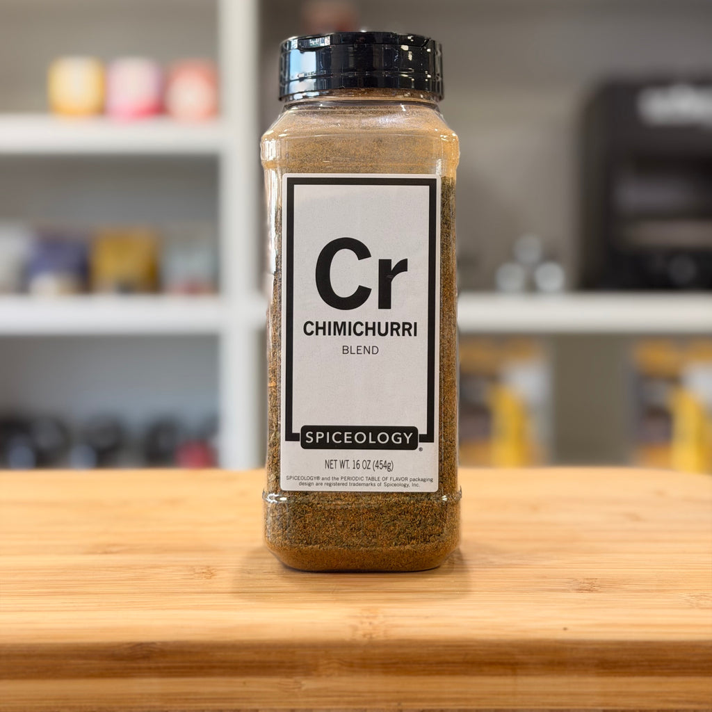 Spiceology Chimichurri blend spice jar on a wooden surface with a blurred kitchen background