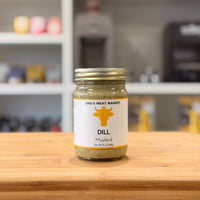 Jar of dill mustard from Chu's Meat Market on a wooden surface with a blurred background