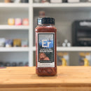 Bottle of Sasquatch BBQ Erubtion spice blend on a wooden surface with a blurred kitchen background.