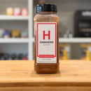 Bottle of habanero ground spice on a wooden surface with a blurred kitchen background