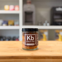 Jar of Korean BBQ spice mix on a wooden surface with a blurred kitchen background