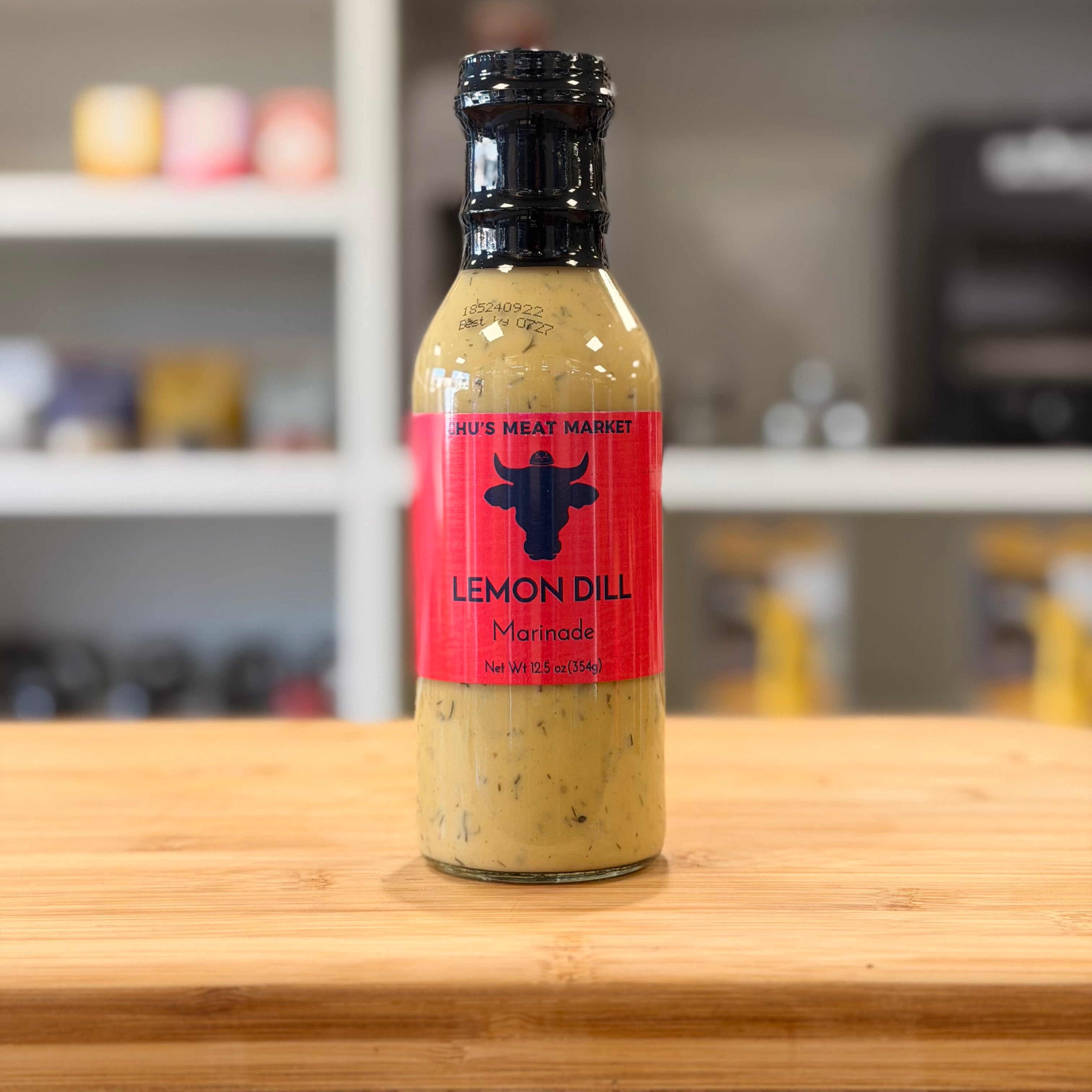 Bottle of lemon dill marinade on a wooden surface with a blurred background