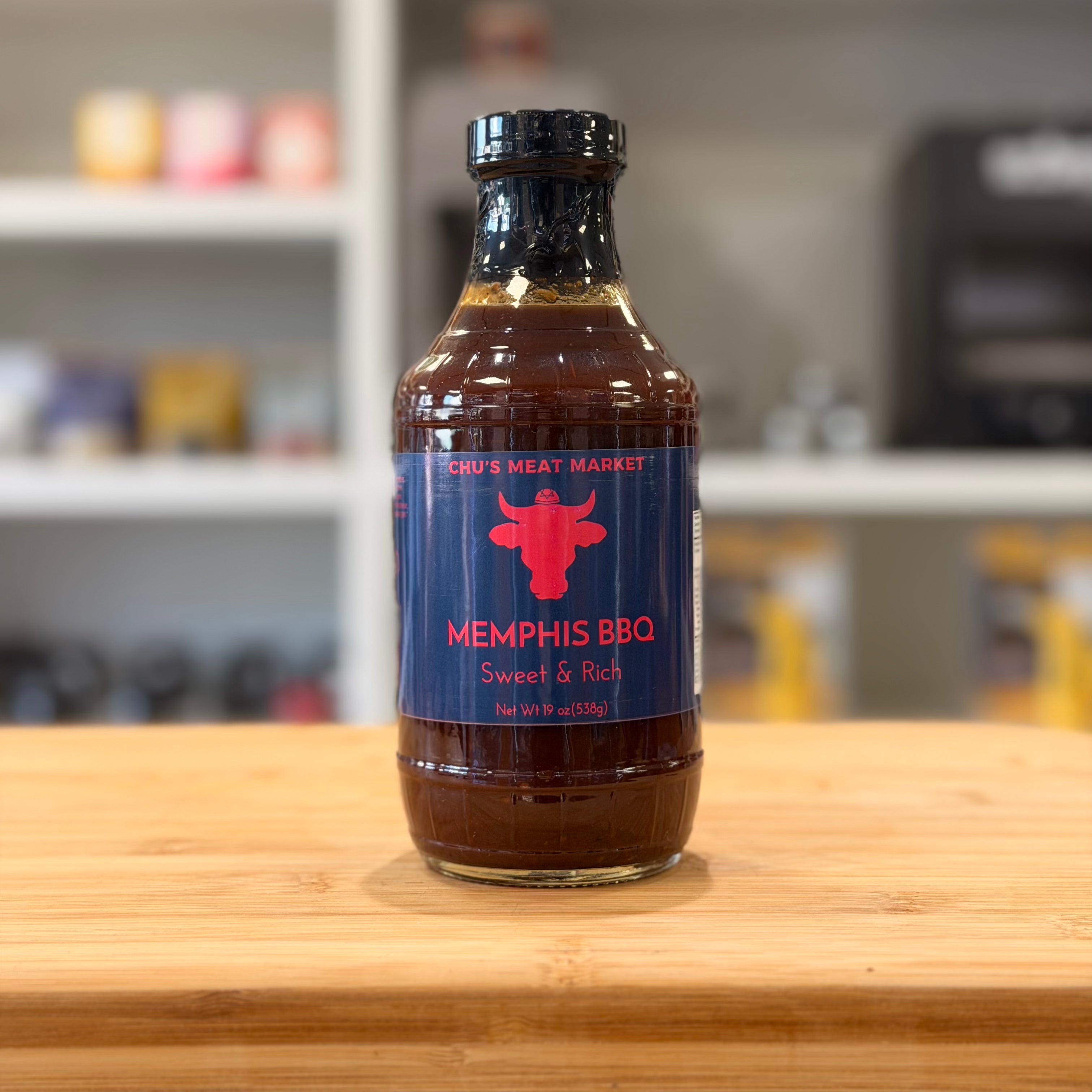 Bottle of Memphis BBQ sauce on a wooden surface with a blurred background
