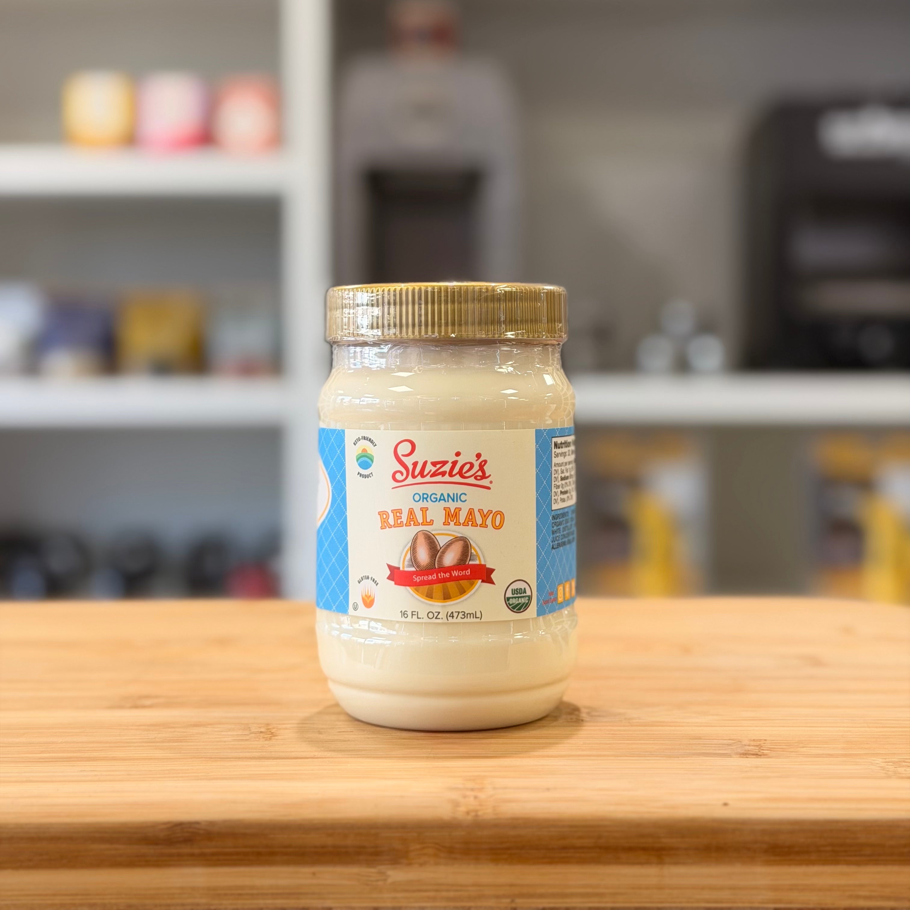 Jar of Suzie's Organic Real Mayo on a wooden surface with a blurred kitchen background