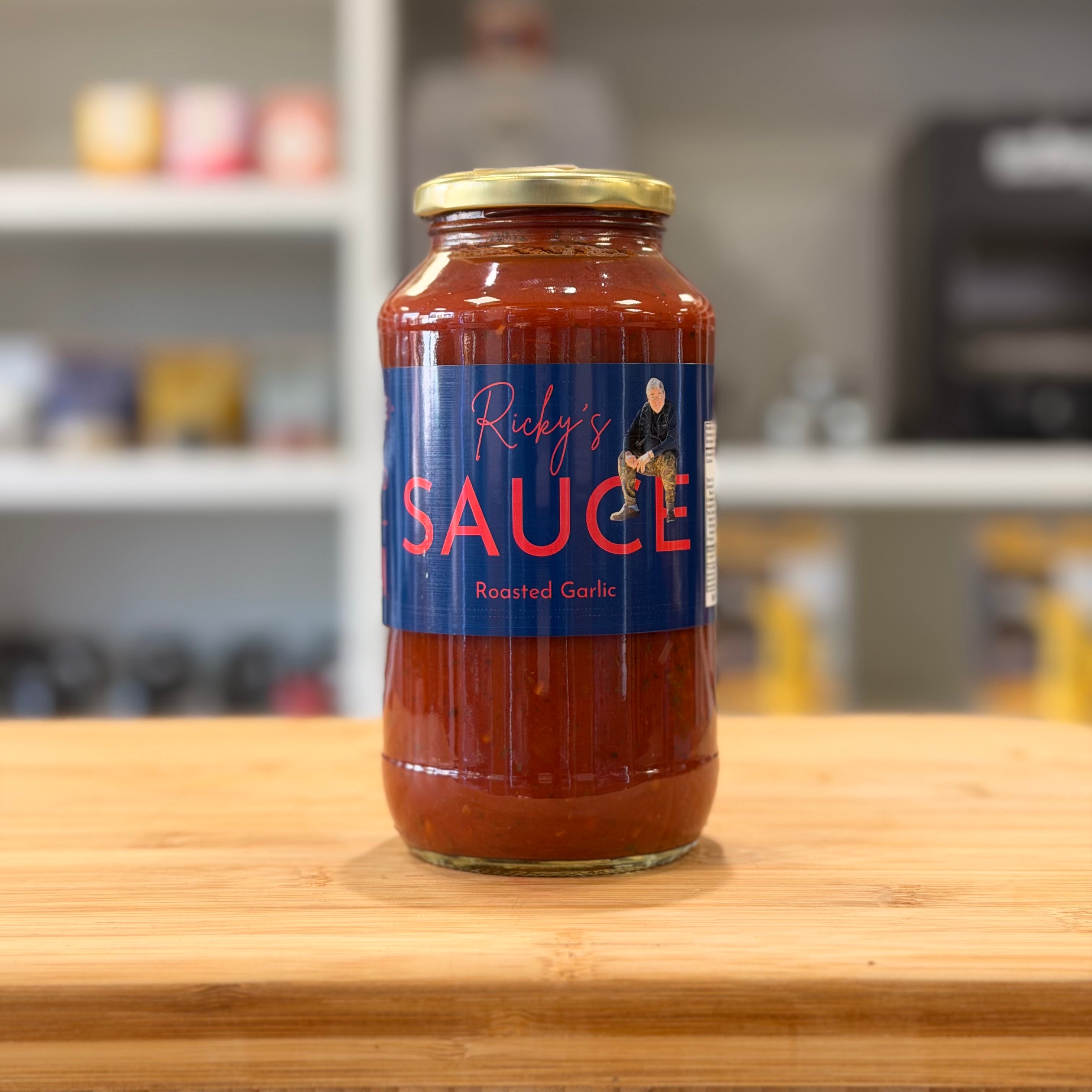 Jar of 'Ricky's Sauce' on a wooden surface with a blurred kitchen background