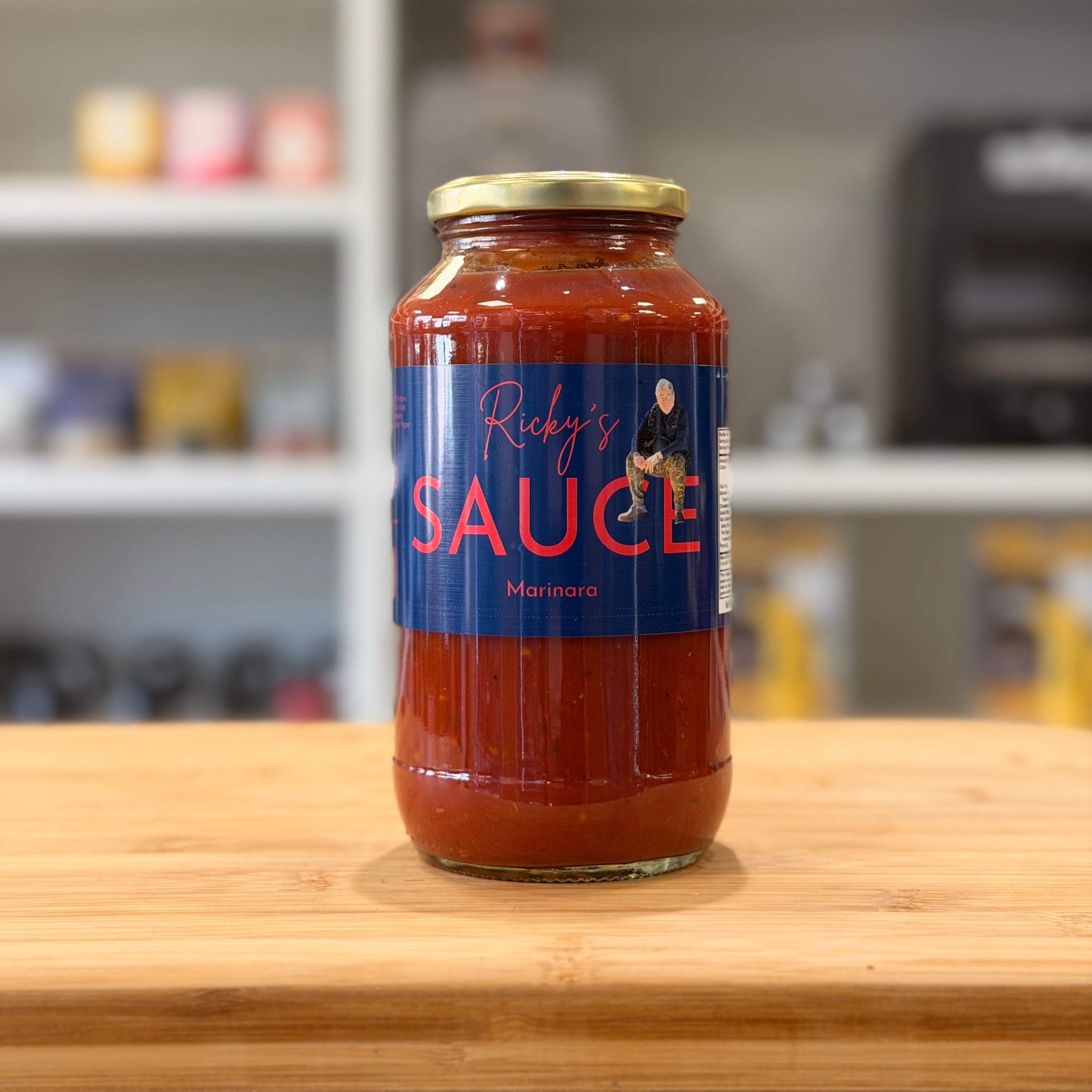 Jar of 'Ricky's Sauce' on a wooden surface with a blurred kitchen background