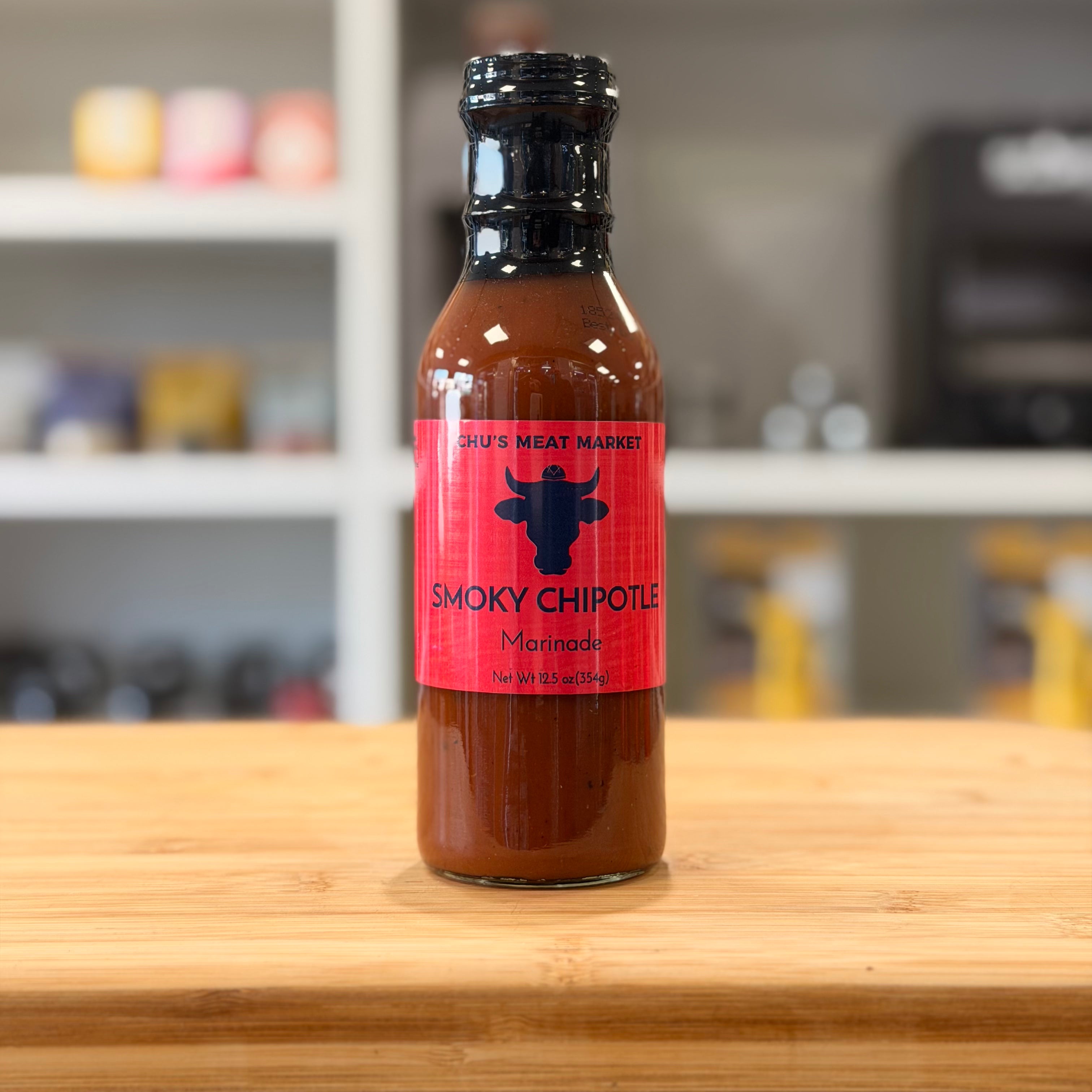 Bottle of Smoky Chipotle Marinade on a wooden surface with a blurred kitchen background