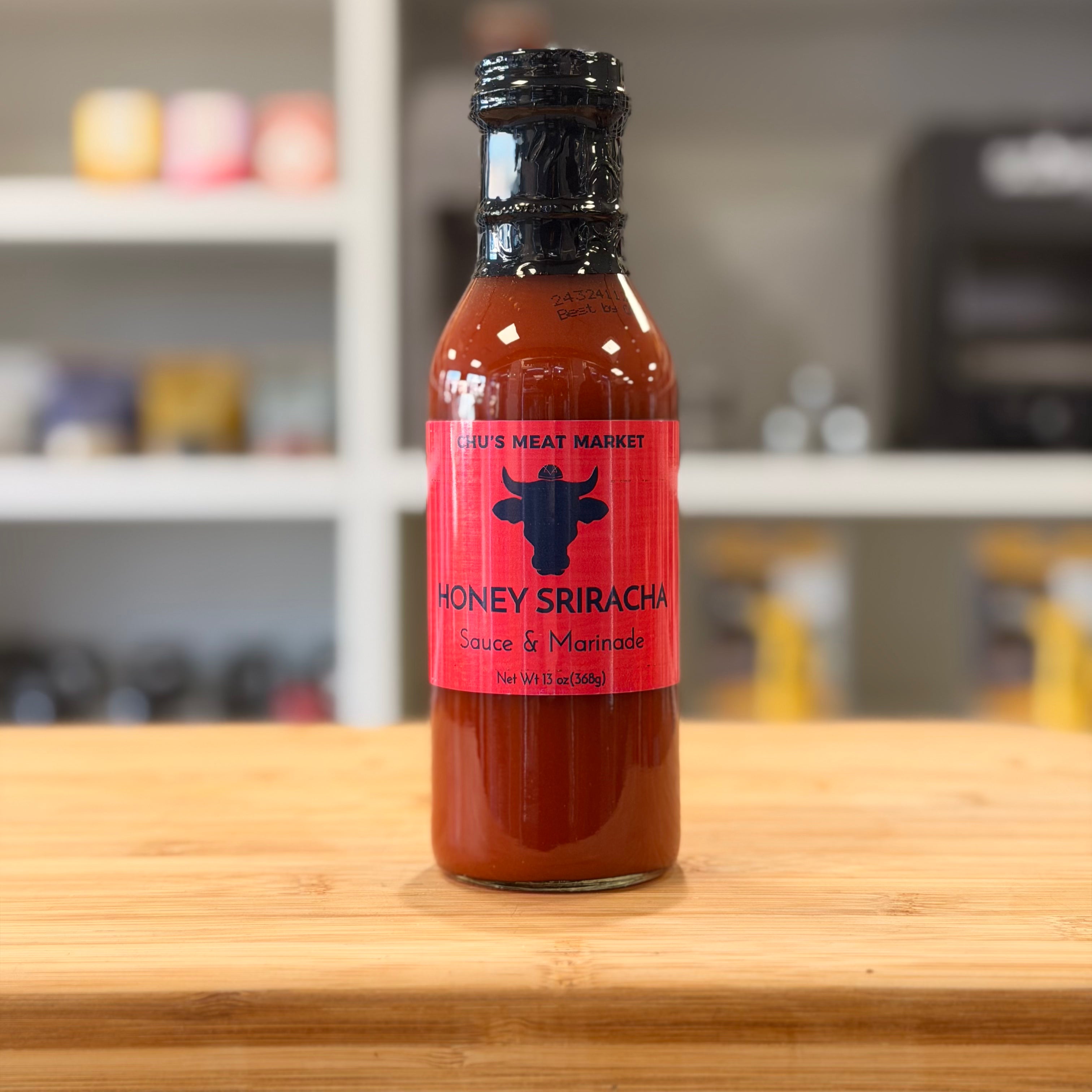 Bottle of Honey Sriracha sauce on a wooden surface with a blurred background