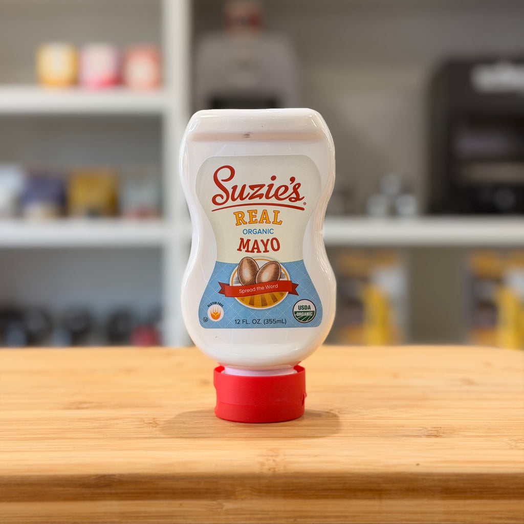 Suzie's Real Mayo bottle on a wooden surface with a blurred kitchen background