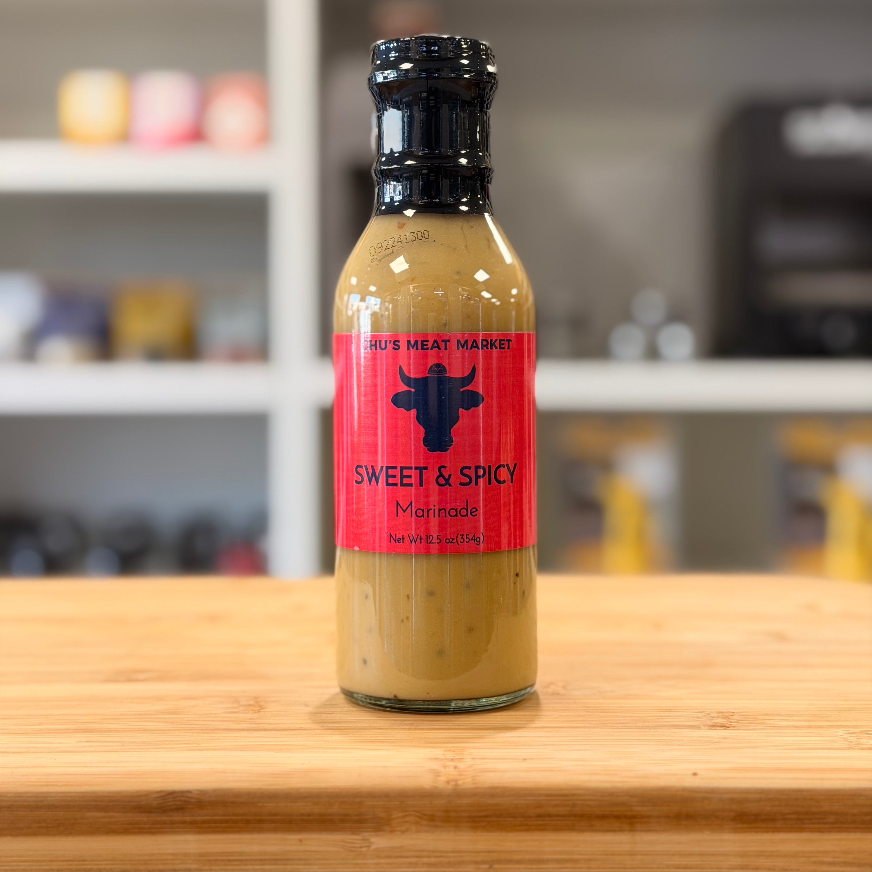 Bottle of 'Sweet & Spicy' marinade on a wooden surface with a blurred background