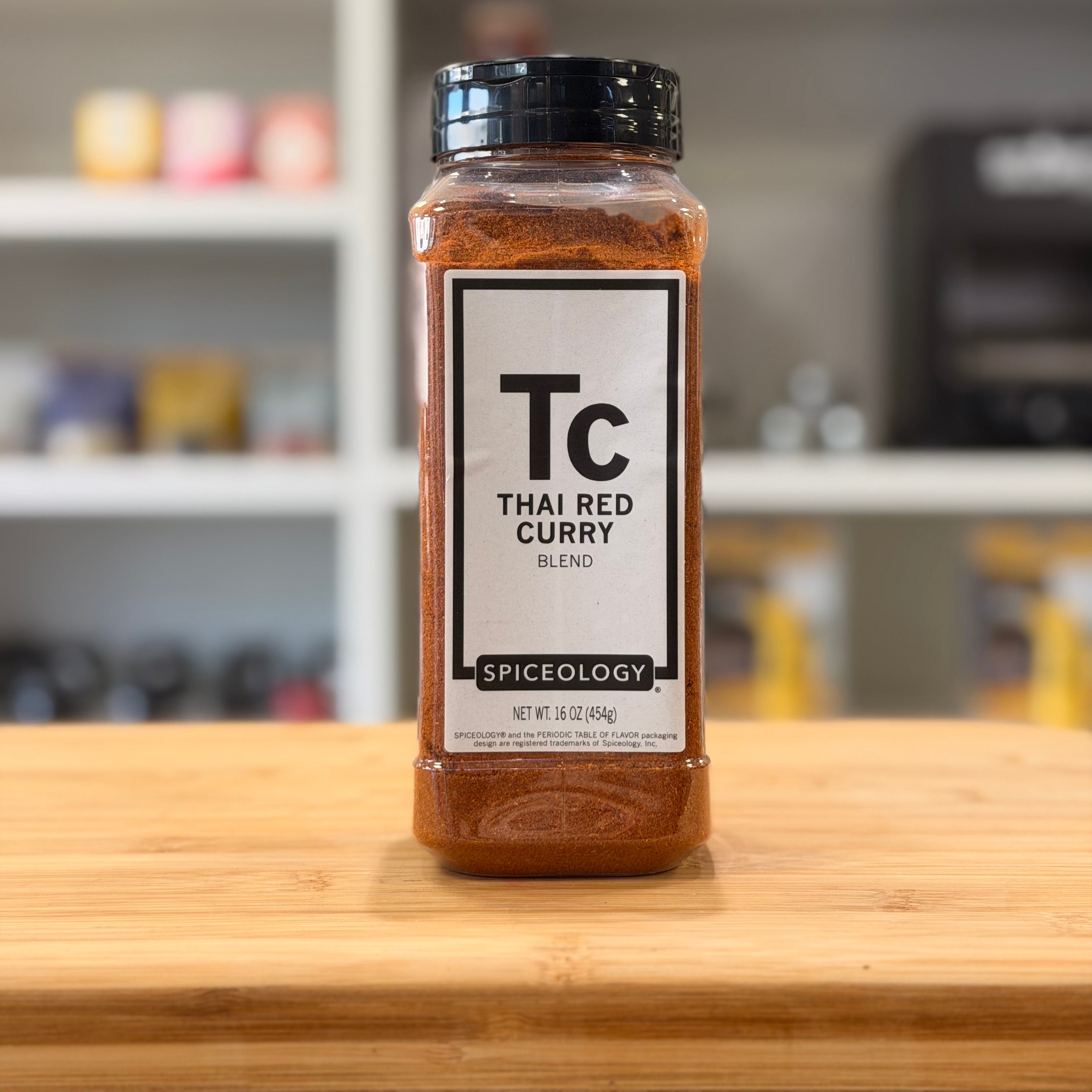 Spiceology Thai Red Curry blend jar on a wooden surface with a blurred kitchen background