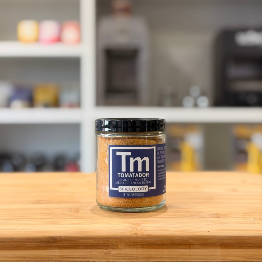 Jar of 'Tomatador' spice on a wooden surface with a blurred kitchen background